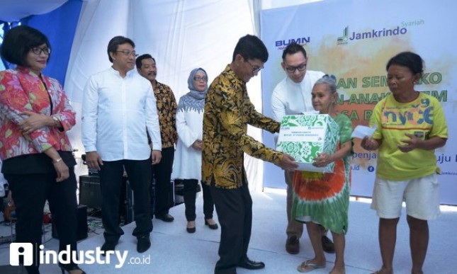 Dirut Jamkrindo Diding S Anwar (tengah), didampingi Direktur Operasional R Sohia Alizsa (kiri) membagikan paket sembako kepada warga di sekitar kantor, di Jakarta, Jumat (16/6), Kegiatan ini sebagai bagian dari program BUMN Hadir untuk Negeri. (Foto