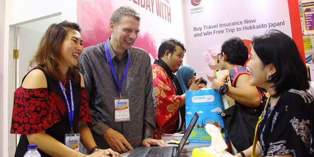 Eric Nemitz (dua kiri) berbincang dengan konsumen di booth Sompo Insurance pada acara Astindo Travel Fair 2018 di Jakarta Convention Center