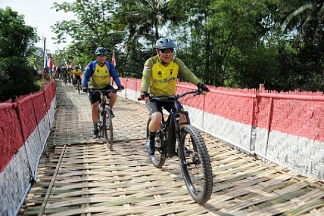 Maryono, Direktur Bank BTN, sedang bersepeda melewati salah satu jembatan pada etape BTN Tour de Borobudur 2018
