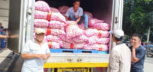 sedang memindahkan bawang putih di Pasar Kramat Jati