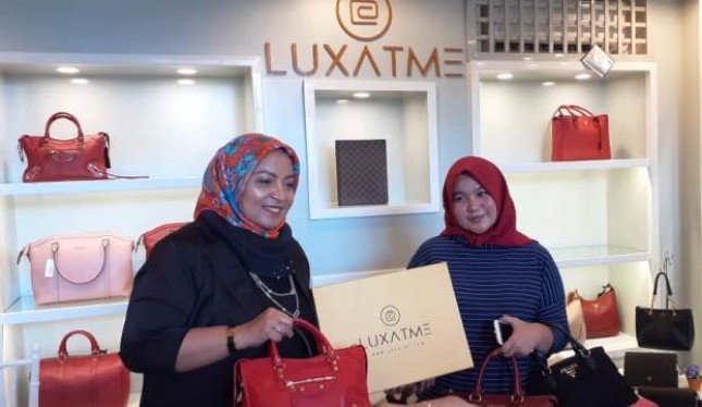 Ade Hanurati (kiri) memperlihatkan sejumlah tas branded yang disukai kalangan milenial di toko Luxatme miliknya.