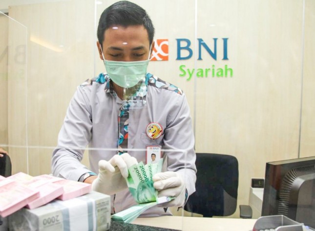 Petugas BNI Syariah di Kantor Cabang Bendungan Hilir, Jakarta sedang melayani penukaran uang nasabah.
