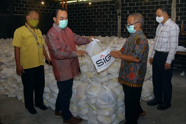 Kepala Departemen CSR SIG, Edy Saraya (kedua dari kiri) menyerahkan paket bantuan kebutuhan pokok kepada tokoh masyarakat, H. Khilmi (kedua dari kanan) di Gresik, Jawa Timur. 