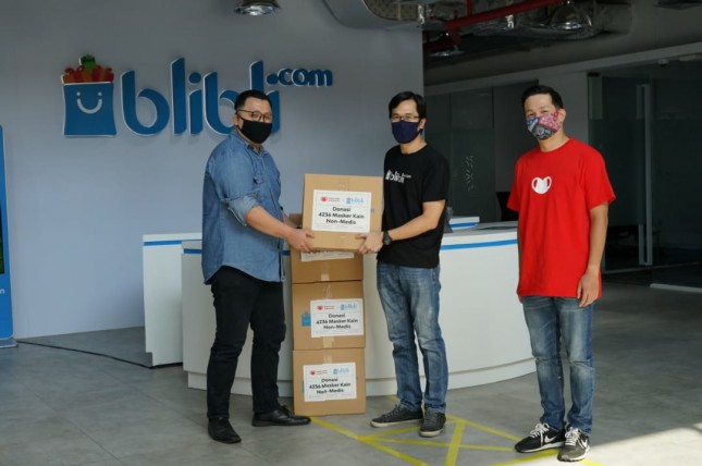Bunadi Lasyim Senior Vice President of General Services Blibli sekaligus ketua Tim Tanggap Corona Blibli (tengah) pada seremoni penyerahan masker kain donasi karyawan Blibli dalam program “Bliblioneers Berdonasi MaskerUntukIndonesia” kepada Nico Agus (Digital Specialist) Relawan Langkah Kasih (kiri), dan disaksikan oleh Kevin Osmond perwakilan relawan Masker Untuk Indonesia (kanan)