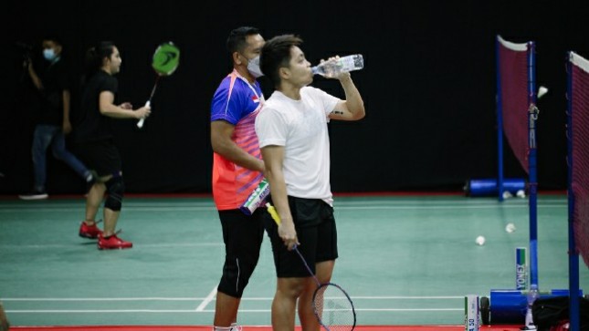 Pemain Badminton meminum air mineral saat berlaga