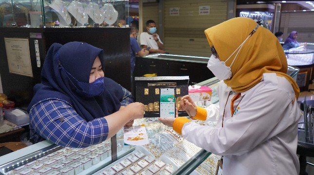 Pegawai PT Bank Syariah Indonesia Tbk (BSI) Kantor Cabang Mayestik sedang menyampaikan penjelasan terkait fitur gadai emas dan cicil emas yang terdapat di BSI Mobile kepada nasabah pemilik toko emas di salah satu kios saat Grebek Pasar BSI di Pasar Mayestik 