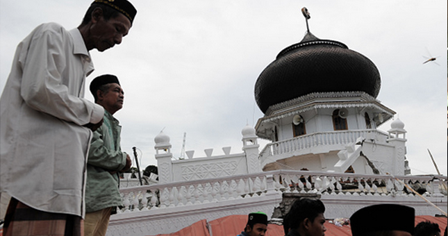 Seorang pria melaksanakan salat Jumat di masjid yang roboh di Pidie Jaya, Aceh. (Chaideer Mahyudin/Getty Images)