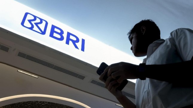 Nasabah melintas di bawah Plang BRI