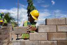 Proses pemasangan inovasi produk turunan semen hijau SIG precise interlock brick dalam pembangunan hunian tapak rumah lingkungan tipe 36 di kawasan Ibu Kota Nusantara (IKN).