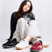 Seorang anak muda percaya diri memamerkan beberapa model sepatu Raingel Footwear.